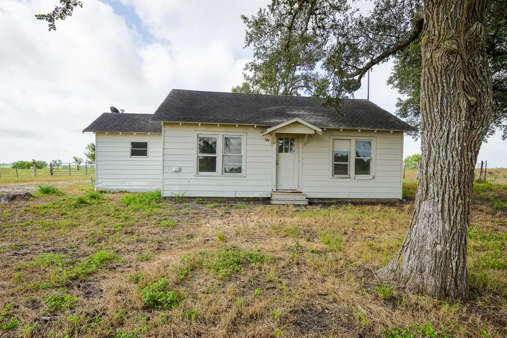 Weathered farmhouse behind an oak tree on Tract 3, La Grange, Texas.